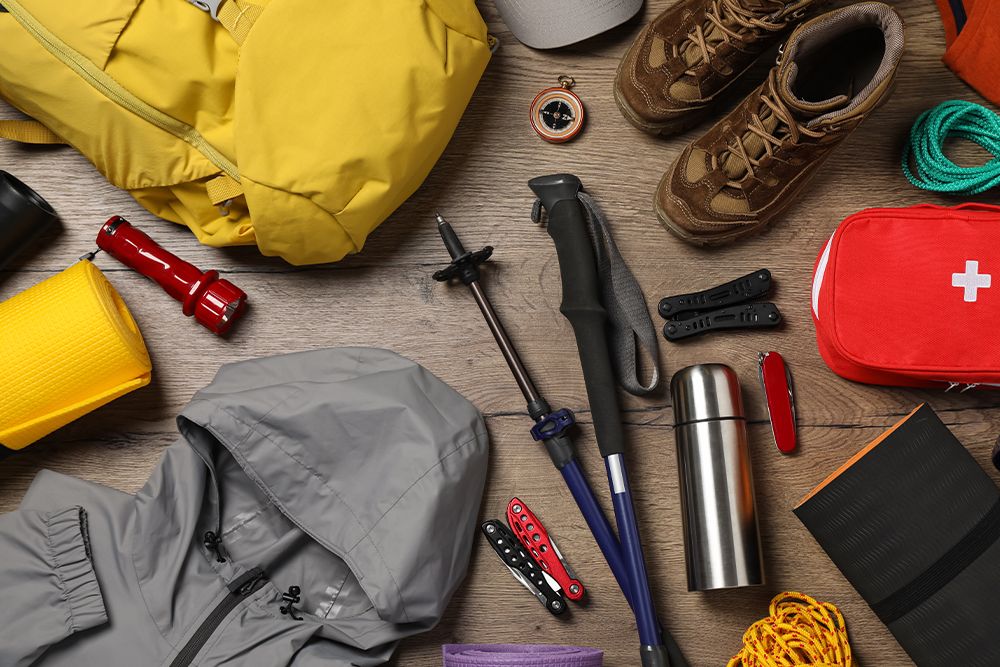 Flat lay composition with trekking poles and other hiking equipment on wooden background